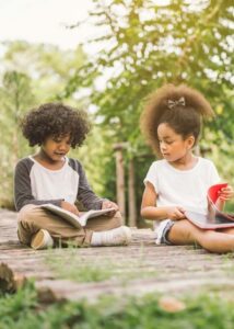 Two kids reading outside