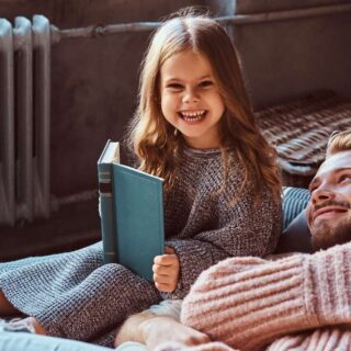 girl holding book smiling next to her dad