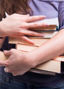 girls hands holding a pile of books