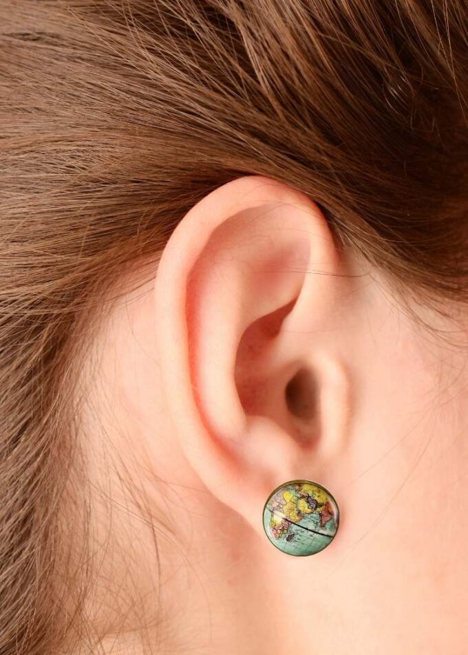 Close up of woman’s ear wearing globe earrings